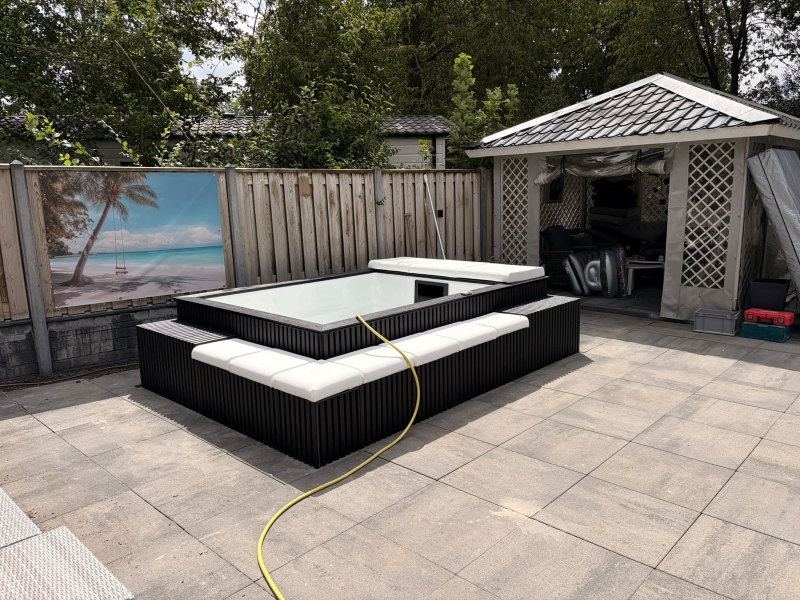 Minipool PRO met zwarte buitenbekleding en witte zitkussens op een terras in Biddinghuizen.