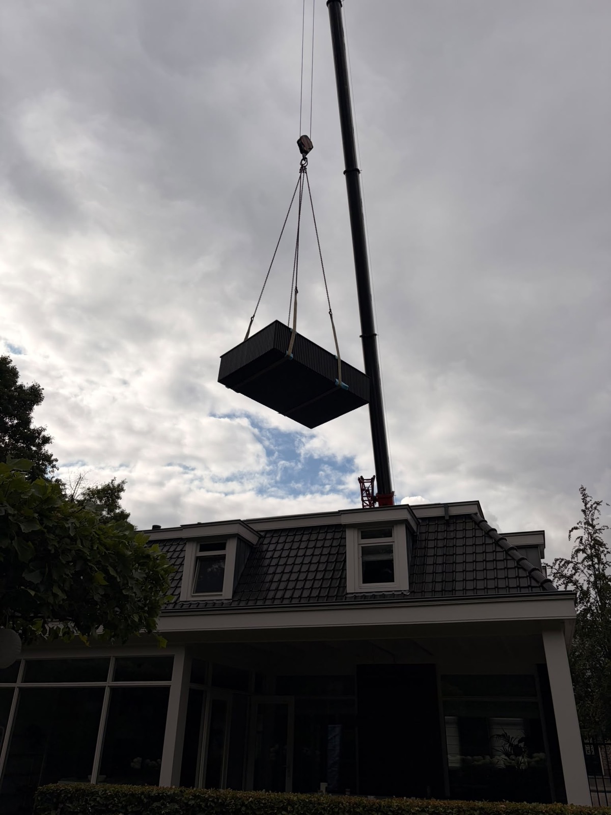 Het bad wordt boven de woning naar de tuin gehesen in Ossendrecht.